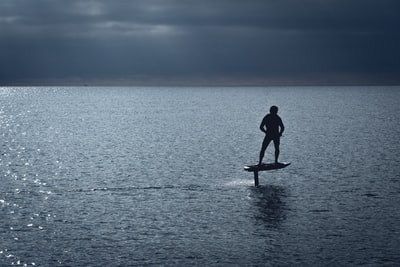 A man dressed in a black wet clothes stood on the brown board during the day
